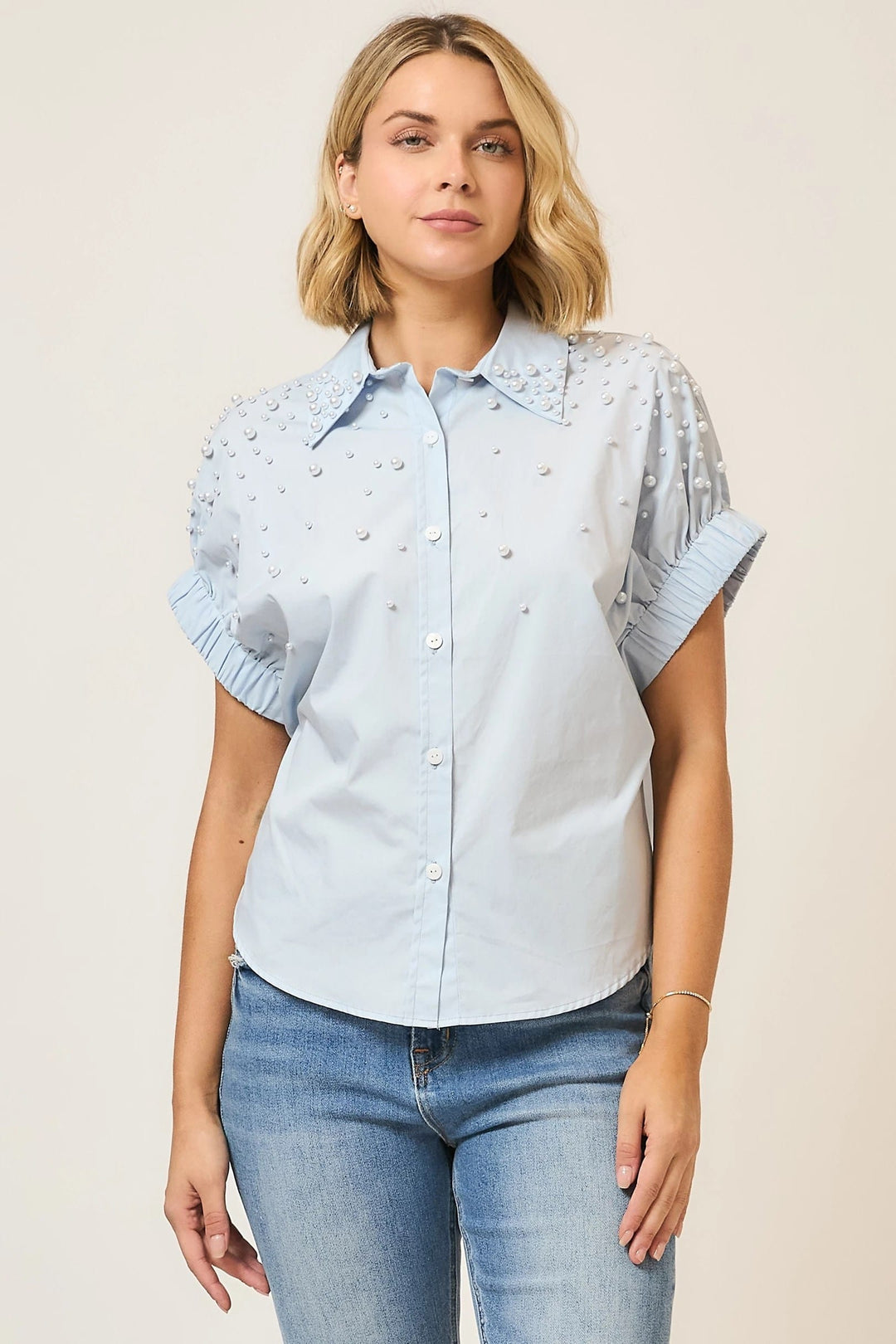 Light blue Cozy Co. Angie pearl-studded button-up top, featuring a classic collar and long sleeves, displayed on a hanger.