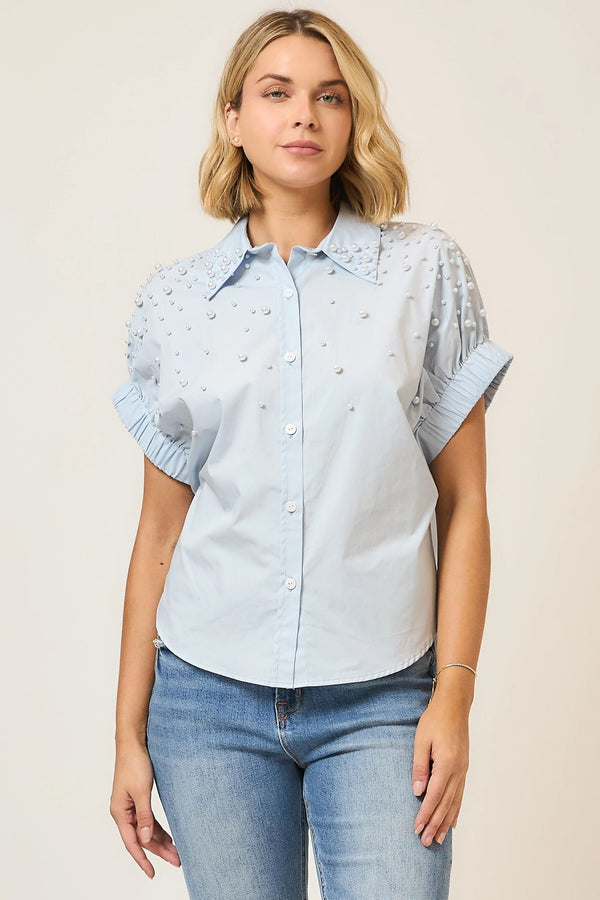 Light blue Cozy Co. Angie pearl-studded button-up top, featuring a classic collar and long sleeves, displayed on a hanger.