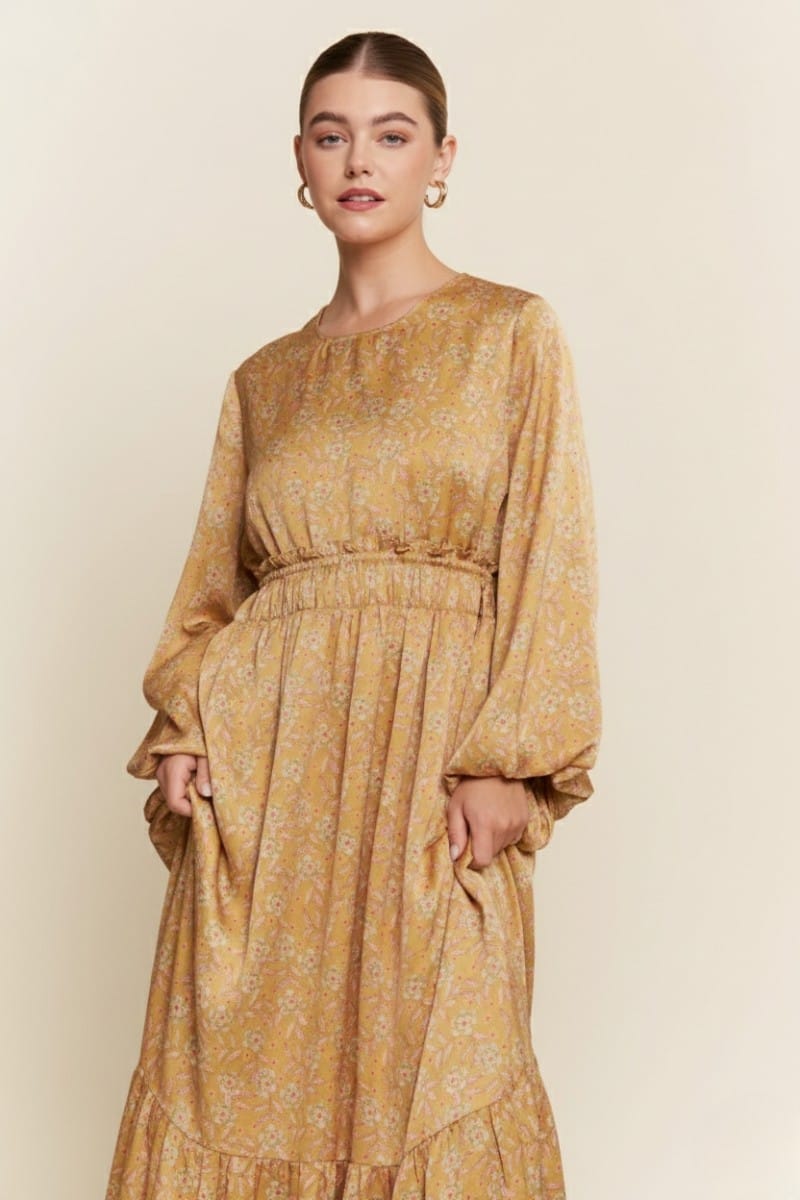 J.NNA Alina Glossy Maxi Dress displayed on a model, featuring a shiny fabric and elegant flowing silhouette.