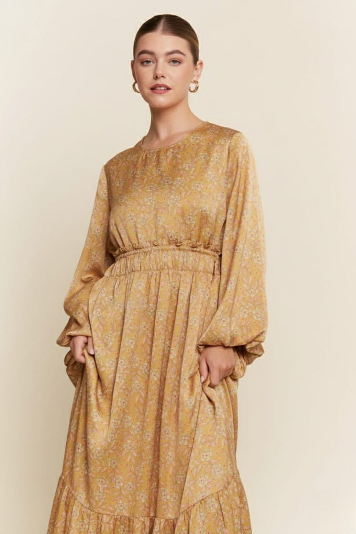J.NNA Alina Glossy Maxi Dress displayed on a model, featuring a shiny fabric and elegant flowing silhouette.