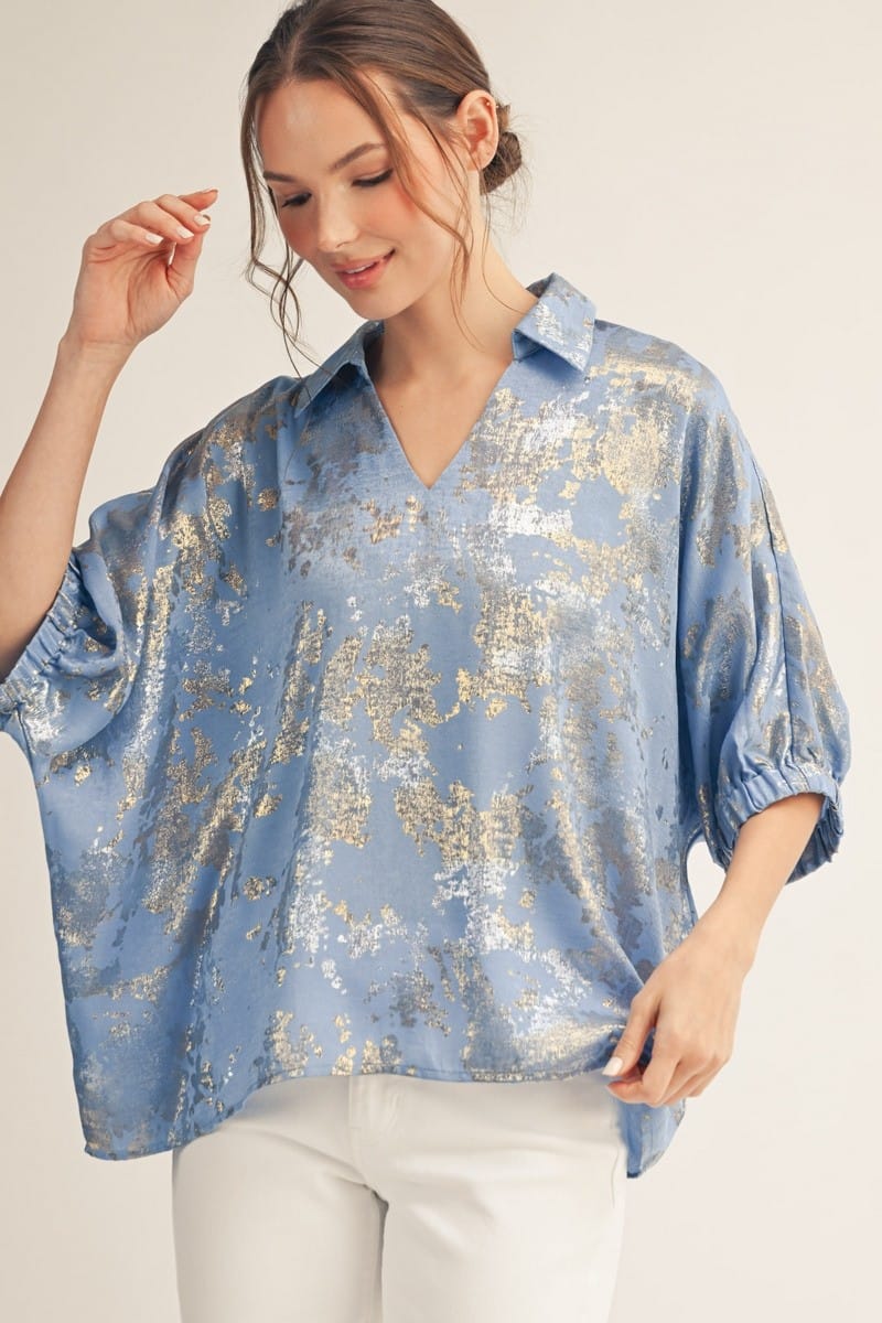 Blue Jodifl Kendra Metallic Top displayed on a hanger showcasing its shiny, textured fabric and stylish sleeveless design.