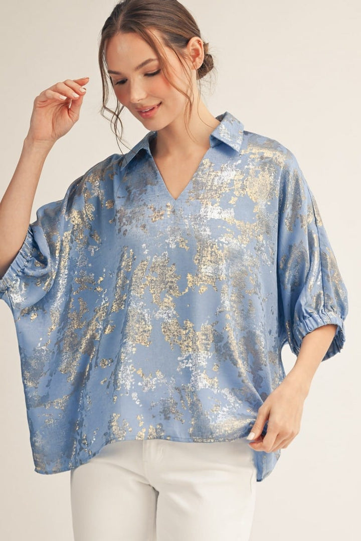 Blue Jodifl Kendra Metallic Top displayed on a hanger showcasing its shiny, textured fabric and stylish sleeveless design.