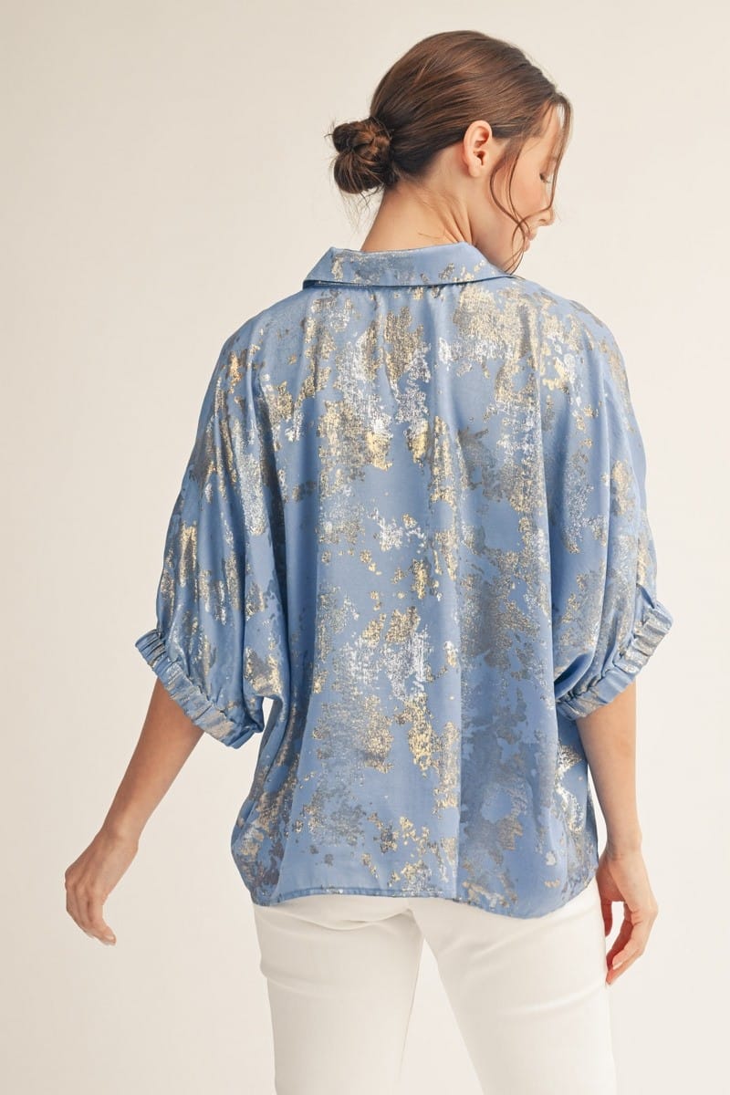 Jodifl Kendra metallic top featuring a shiny, metallic fabric with a stylish neckline, displayed on a hanger against a neutral background.