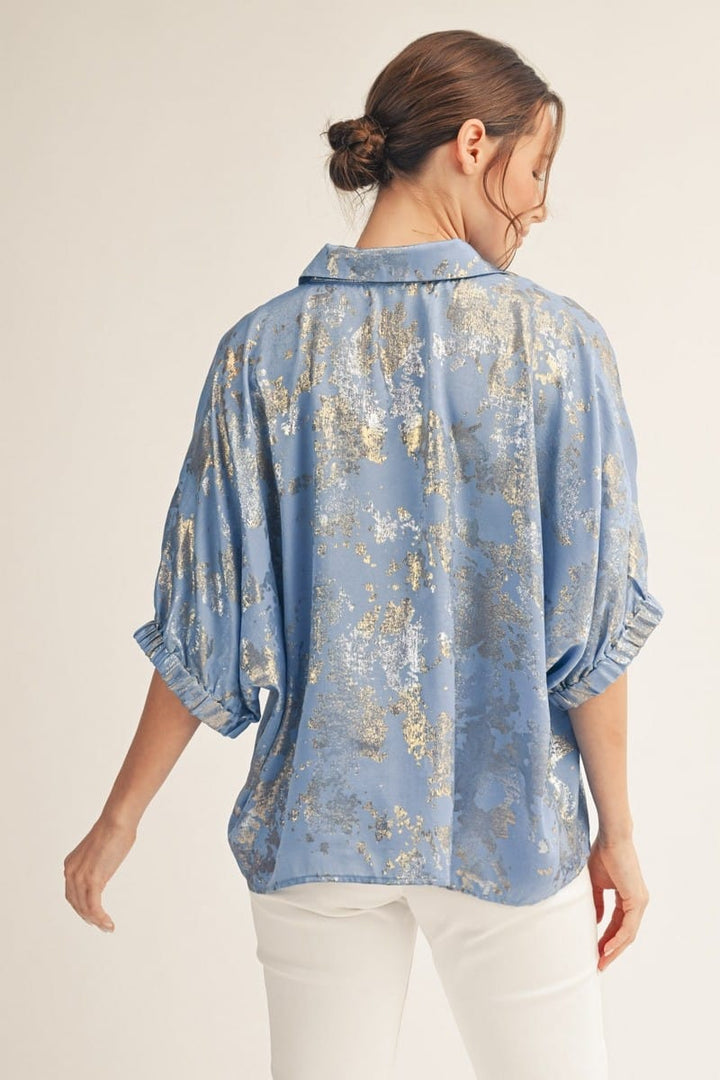 Jodifl Kendra metallic top featuring a shiny, metallic fabric with a stylish neckline, displayed on a hanger against a neutral background.