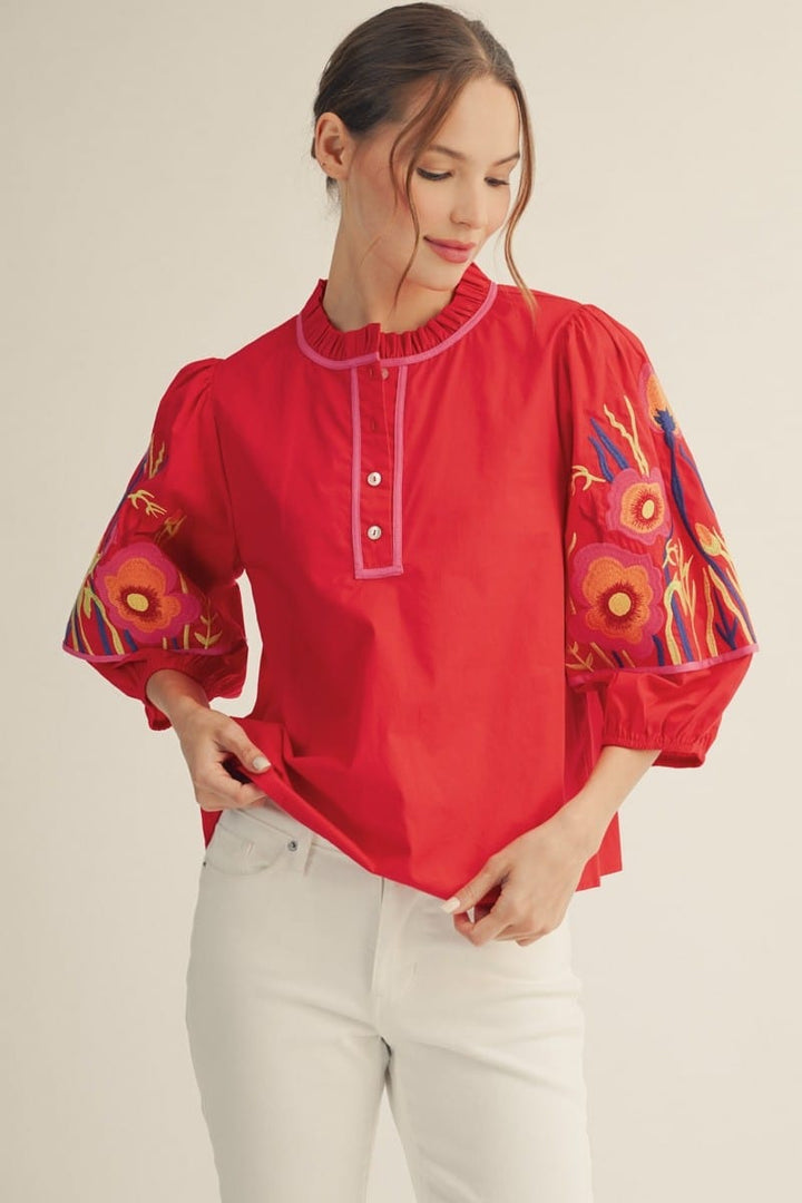 Jodifl Jillian embroidered top in tomato red, featuring detailed embroidery and a stylish fit, displayed on a hanger.
