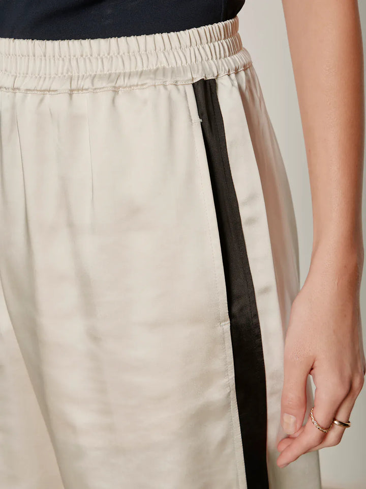 Sanctuary Angel Satin Track Pant featuring a relaxed fit, satin fabric, and elastic waistband, laid flat on a neutral background.